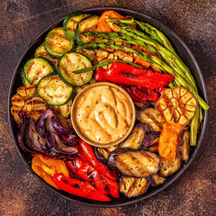 Grilled vegetables on a plate with sauce.