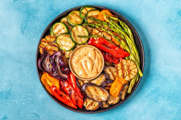 Grilled vegetables on a plate with sauce.