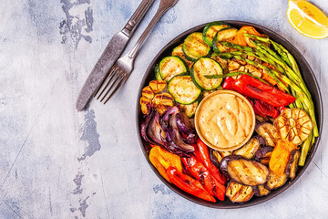 Grilled vegetables on a plate with sauce.