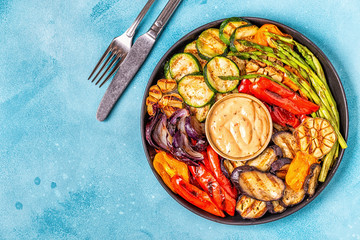 Grilled vegetables on a plate with sauce.