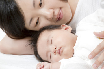 Obraz na płótnie Canvas 新生児と添い寝しながら赤ちゃんの旨に手を添える若いお母さん、親子の愛と幸せ、母性イメージ