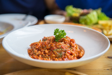Spaghetti with minced pork tomato sauce on white dish in restaurant