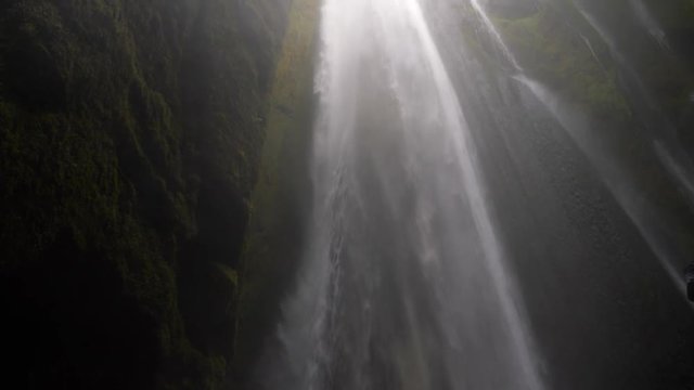 Pan up of majestic waterfall in cave in Iceland