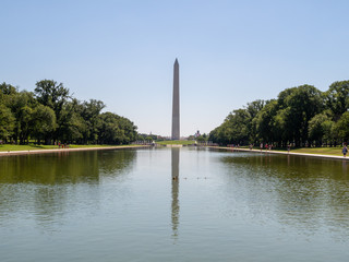 Washington Monument in front of the reflecting pool on National Mall on sunny day