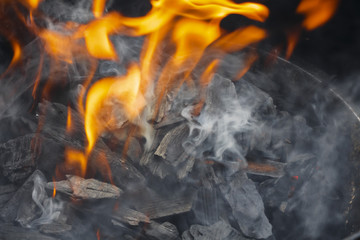 Burning charcoal close-up. Coal in fire and smoke. 
Bonfire. Fire wood. Grilling and cooking fire. Woodfire with flames.