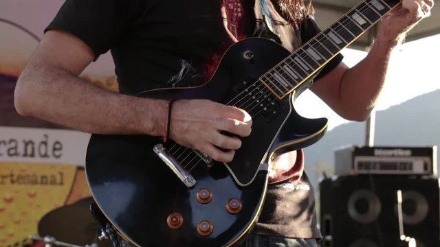 a close up of a guitar player playing with a green and nature background on a energic music festival