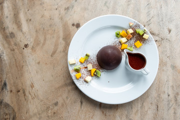 Chocolate cocoa dome dessert with slices fruits