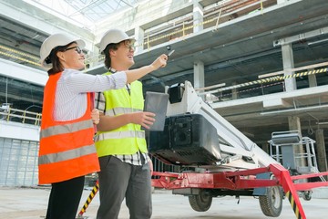 Woman architect and man builder at a construction site. Building, development, teamwork and people concept