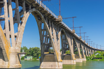 Summer landscape with an old Merefo-Hersonsky arched bridge over Dnipro river in center of the same name city, Ukraine © Yuri Kravchenko