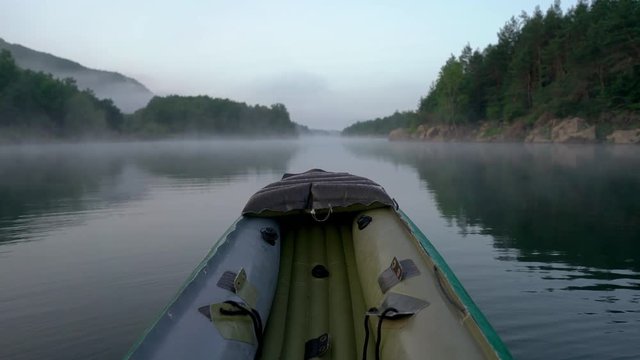 Calm morning on river from canoe and fog on water before sunrise