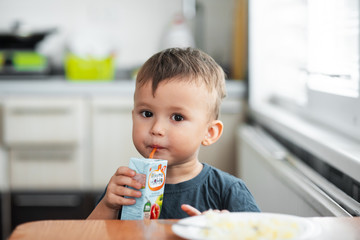 The little boy in the kitchen eagerly eating rice with a spoon independently