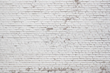 Wall from a white brick with a regular laying with scratched surface