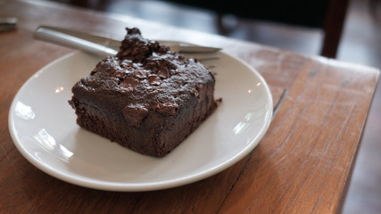 Closeup homemade dark chocolate brownies with almond slices and chocolate sauce on wooden table