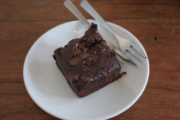 Closeup homemade dark chocolate brownies with almond slices and chocolate sauce on wooden table