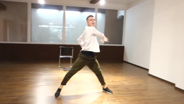 Young handsome man dancer performs moves in dance studio