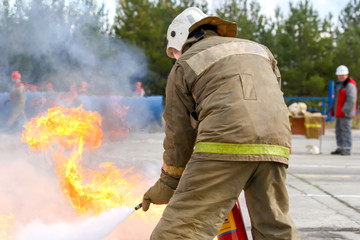 Competitions firefighters. The fireman works with a fire extinguisher to extinguish the fire...