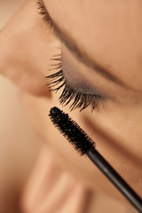 Closeup of young woman applying mascara