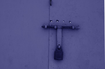 Old padlock on metal gate in blue color.