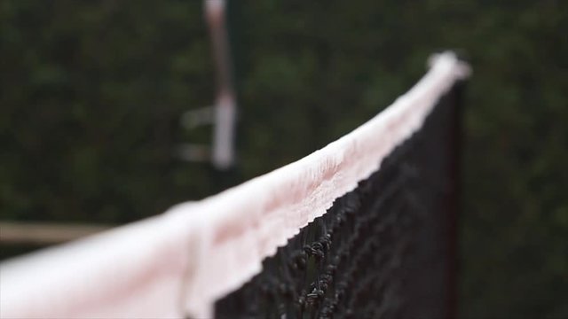 Side Angle Shot of Yellow Tennis Balls fly over the net and hits the net.