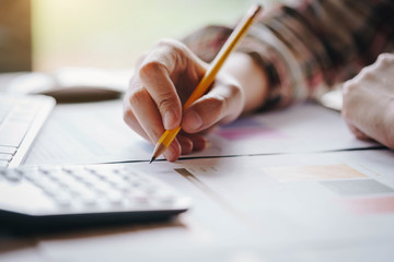 Businesswoman hands holding pen working  with calculator for calculate business profits turnover business. Business financial analysis and strategy concept.