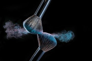 Make up brush with powder splashes on black background