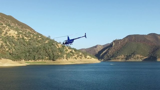 A helicopter circles above a pristine mountain lake.