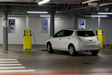 Electric car is charged at the charging station in the underground parking lot