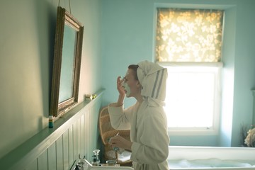 Woman applying facial mask in bathroom
