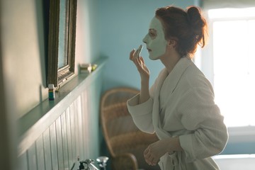 Woman applying facial mask at home