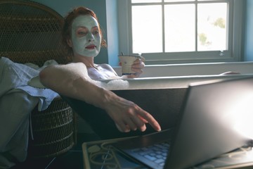Woman using laptop in bathtub