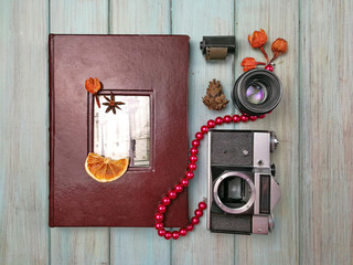 Flat lay. Album with photos from travel. Photo album with a camera and a lens on a light blue painted wooden background. Old photoalbum. Nostalgia