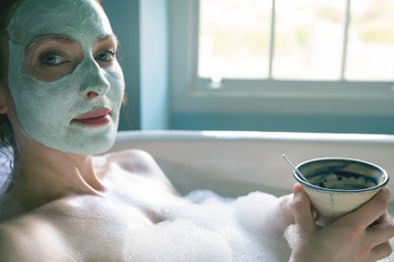 Woman with coffee cup in bathtub