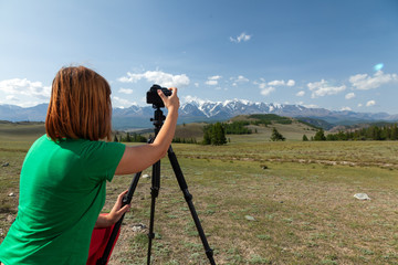 Travel photographer taking nature photo of mountain landscape. Hiker tourist professional woman on adventure vacation shooting slr camera on tripod.