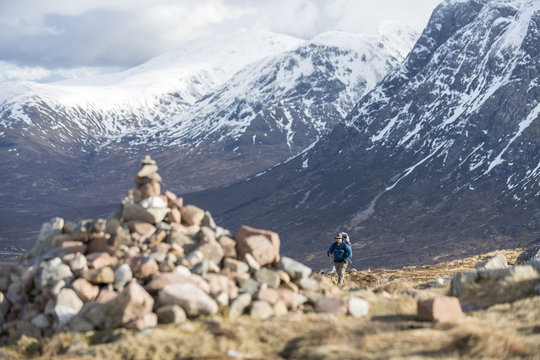A cairn and a walker at the top of the Devils Staircase while hiking along the West Highland Way near Glencoe in the Scottish Highlands, Scotland