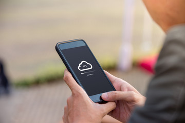 Cloud uploading concept on phone screen. Man hold phone doing cloud uploading at the outdoor.