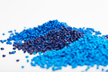 Stacks of a blue plastic polymer granules on a white background, copy space