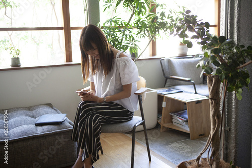 綺麗なオフィスでスマホをいじる女性社員 Wall Mural Monet