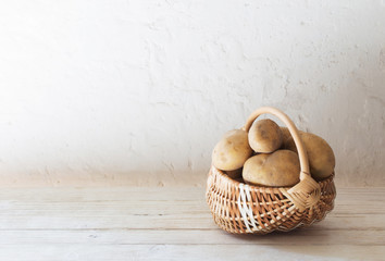 potatoes in basket on background white old wall