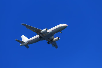 Fototapeta na wymiar A white airplane flying in clear pale blue sky.