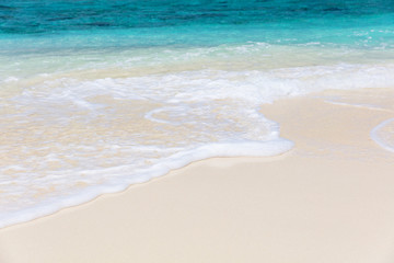 Fototapeta na wymiar White sandy beach and blue foamy sea