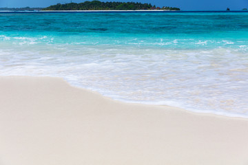 White sandy beach and blue foamy sea