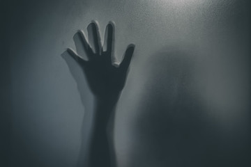 Horror ghost girl behind the matte glass in black and white. Halloween festival concept.