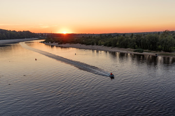horizontal landscape of watery surface with a hydrocycle in the rays of the orange sunset