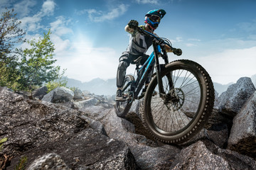 Mountain biker on stone trail. Male cyclist rides the rock - obrazy, fototapety, plakaty