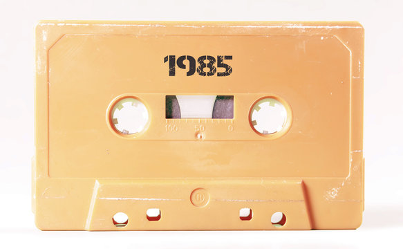 A vintage cassette tape from the 1980s era (obsolete music technology) labeled 1985 (my addition, not in the original image). Color: cream, sand. White background.
