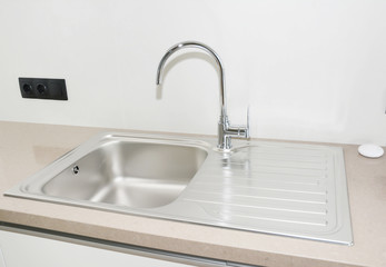 Close up on modern kitchen metal faucet and metal basin kitchen sink .
