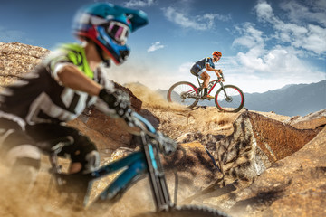 Naklejka na ściany i meble Two bikers on mountain trail. Male cyclists rides the rock. Mountain Bike. Cross-Country Cycling