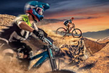 Naklejka na ściany i meble Two bikers on mountain sunset trail. Male cyclists rides the rock. Mountain Bike. Cross-Country Cycling
