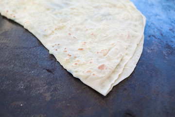 Pita bread with cottage cheese and greens. Preparing traditional bread on the street market.