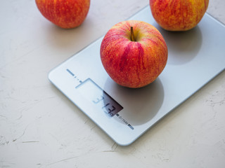 Red apples on kitchen scales on white background. Product weighing